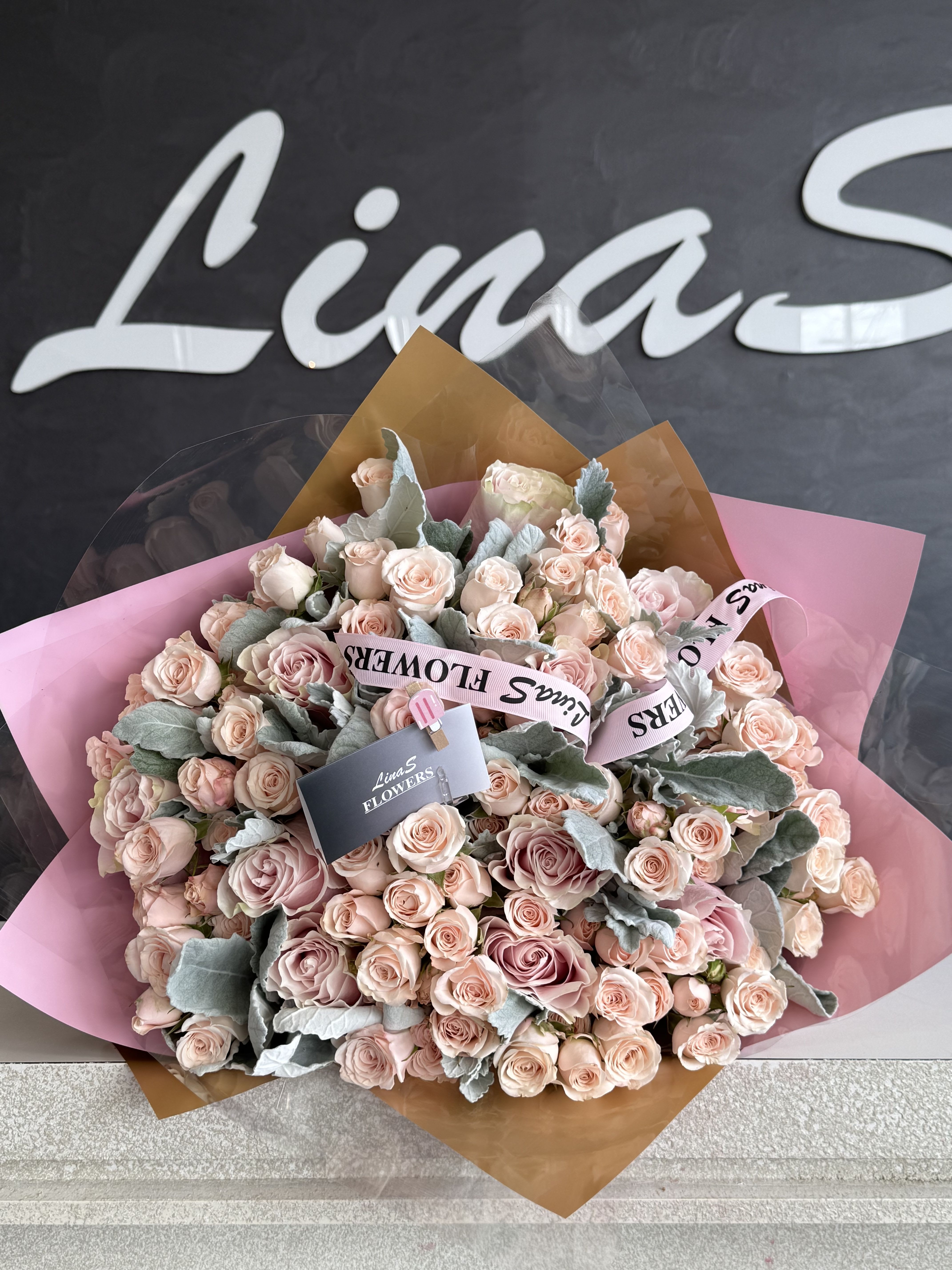 Large bouquet of pale pink roses wrapped in pink and brown paper