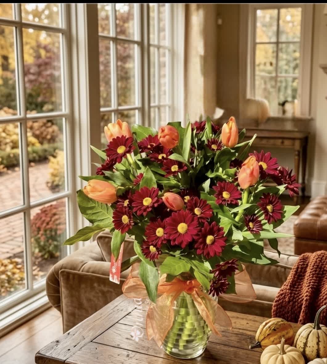 Bouquet of burgundy daisies and peach tulips in a glass vase