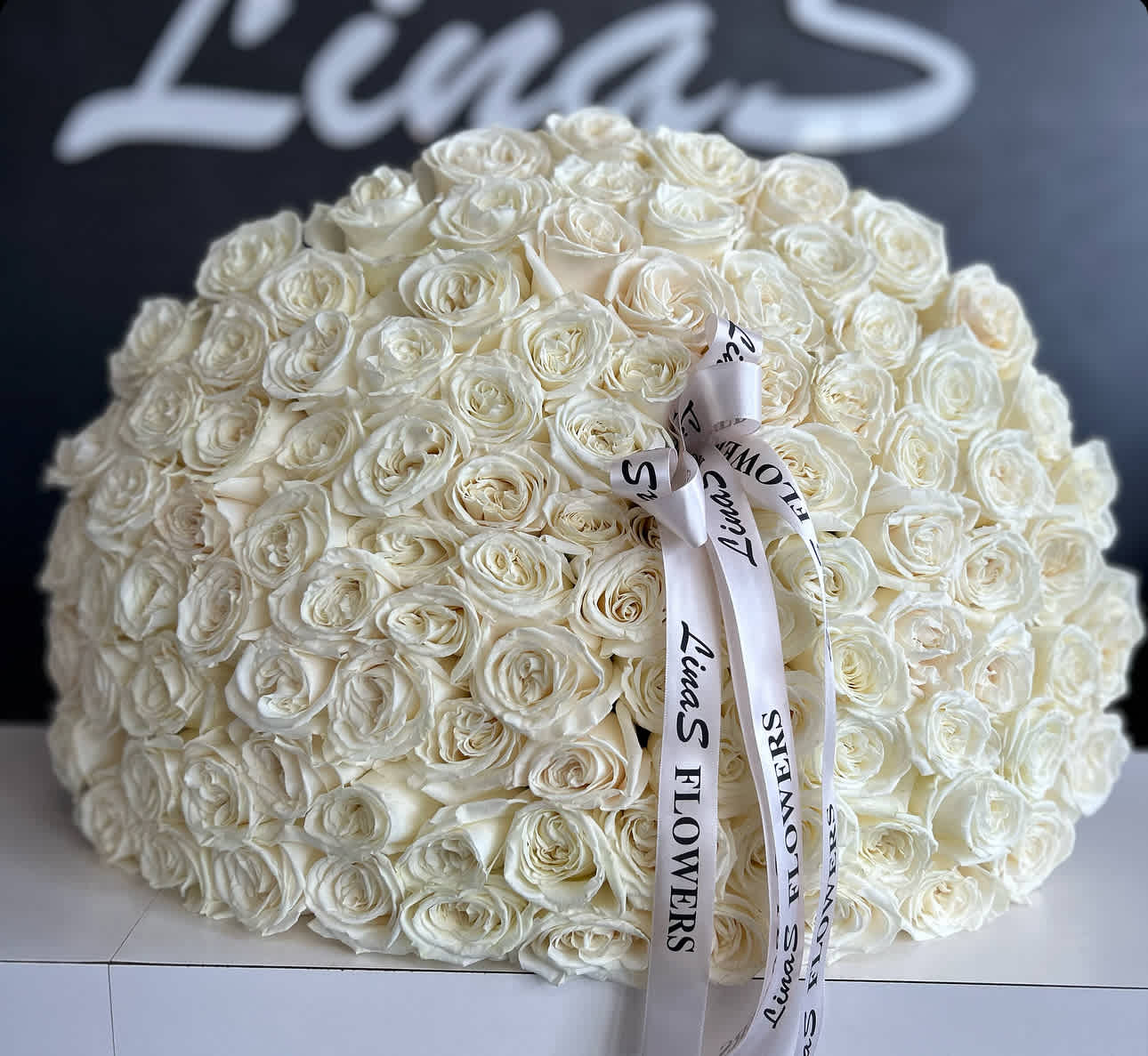 Large dome bouquet of white roses with a printed ribbon bow