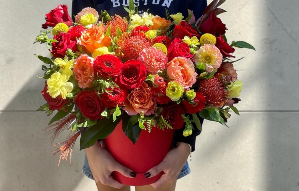 Large mixed bouquet in a red hatbox held by a person