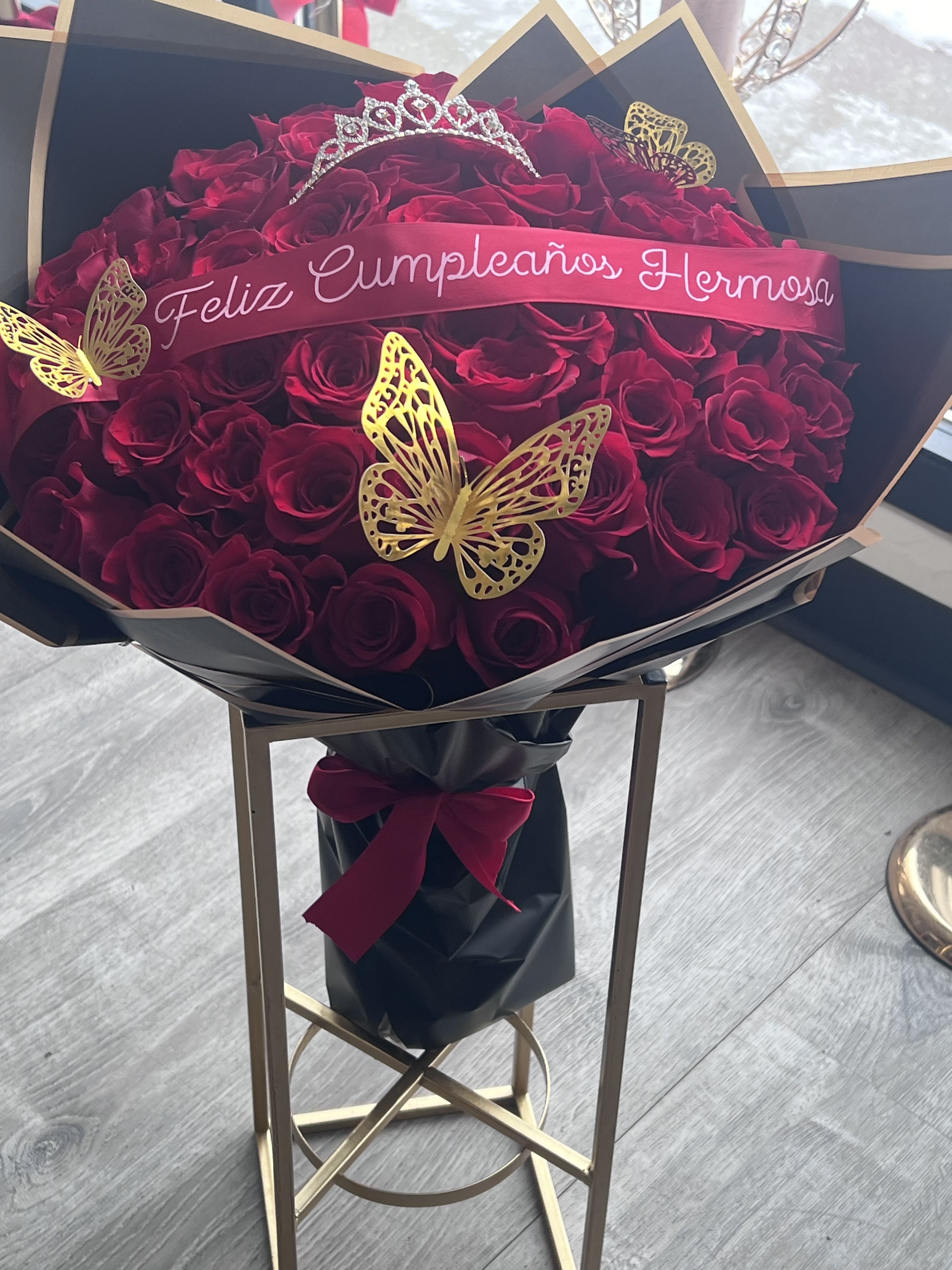 Feliz Cumpleaños Red Rose Arrangement in Black Paper - A bold block of deep red roses packed tightly into a black bouquet box makes an unforgettable birthday bouquet for the person you want to celebrate. This Feliz Cumpleaños red rose arrangement in black paper reads as both romantic and festive-perfect for a birthday or a Valentine's Day surprise-and the rich, velvety petals create a striking monochrome look softened by a bright red ribbon across the center that announces the occasion.  Choose the size that fits your message: Standard with 24 red roses, Deluxe with 50 red roses, or Premium with 100 red roses; each option arrives arranged densely in the black presentation box for maximum visual impact. The presentation includes the black bouquet box and a red ribbon for a polished, gift-ready finish that feels formal yet personal. The compact box keeps the roses close together for a lush, textured surface that makes the recipient feel truly celebrated.  Send this arrangement to make someone in Saint Paul, MN feel cherished on their birthday or to mark a romantic milestone-she'll feel seen, admired, and celebrated the moment the box is opened. For best enjoyment, keep roses in a cool spot away from direct sun and refresh water as recommended if you transfer stems to a vase. Order in time for the date you need and let us handle the elegant presentation.
