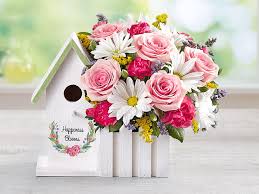 Pink roses and white daisies arranged in a white birdhouse planter