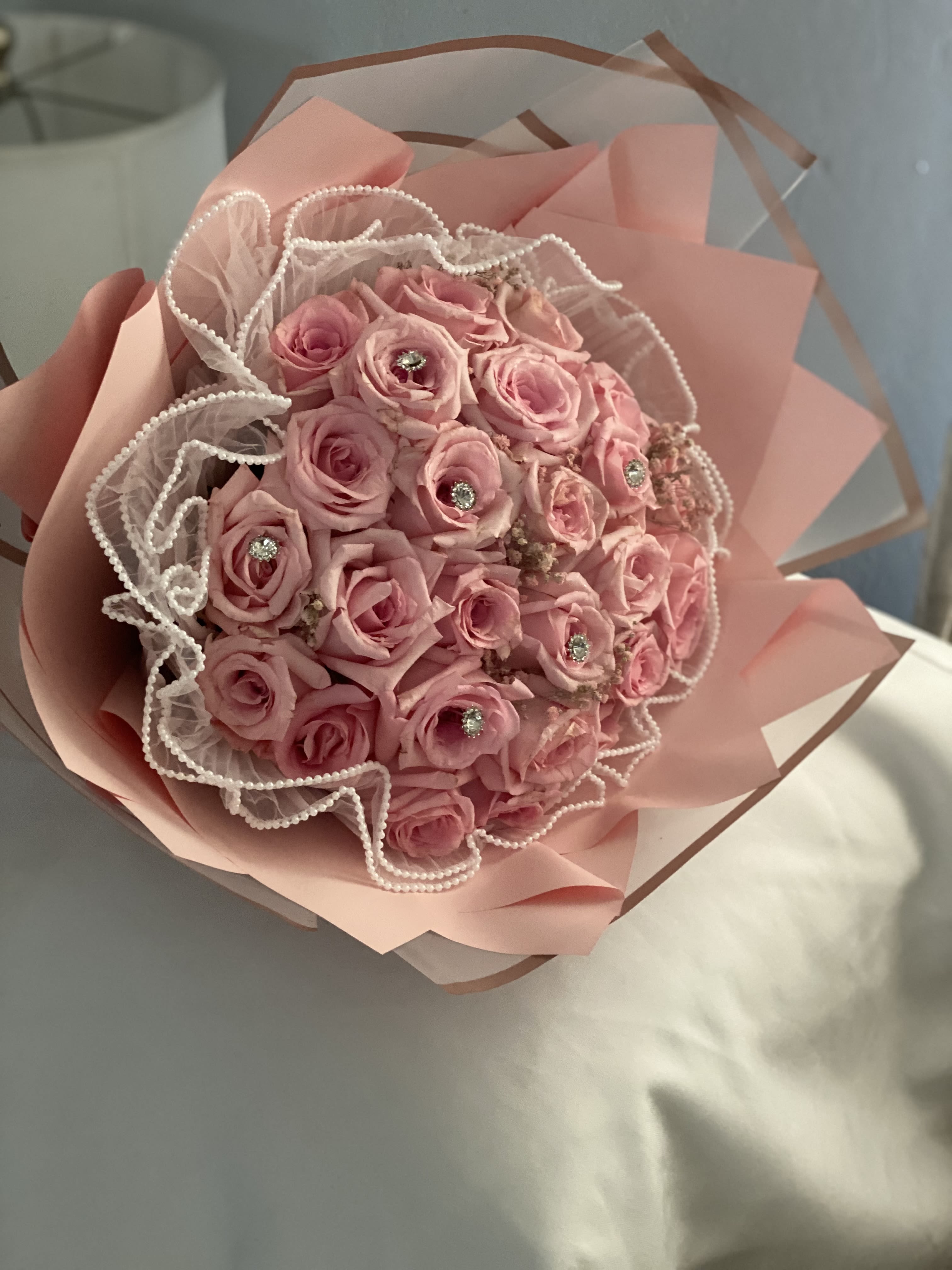 Pink rose bouquet wrapped in blush paper with pearl-edged tulle