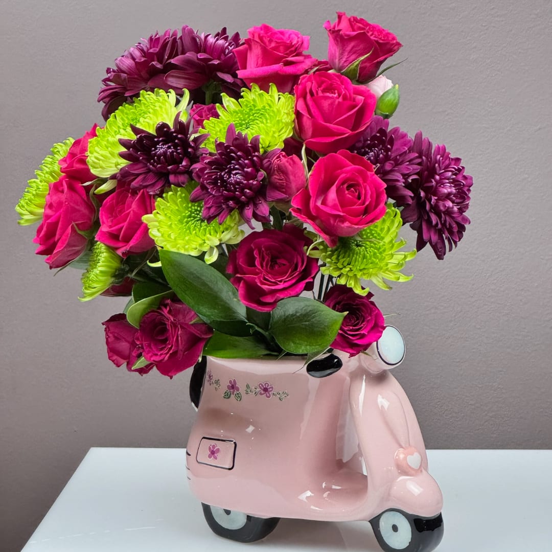 Pink roses and purple chrysanthemums in a pink scooter-shaped vase