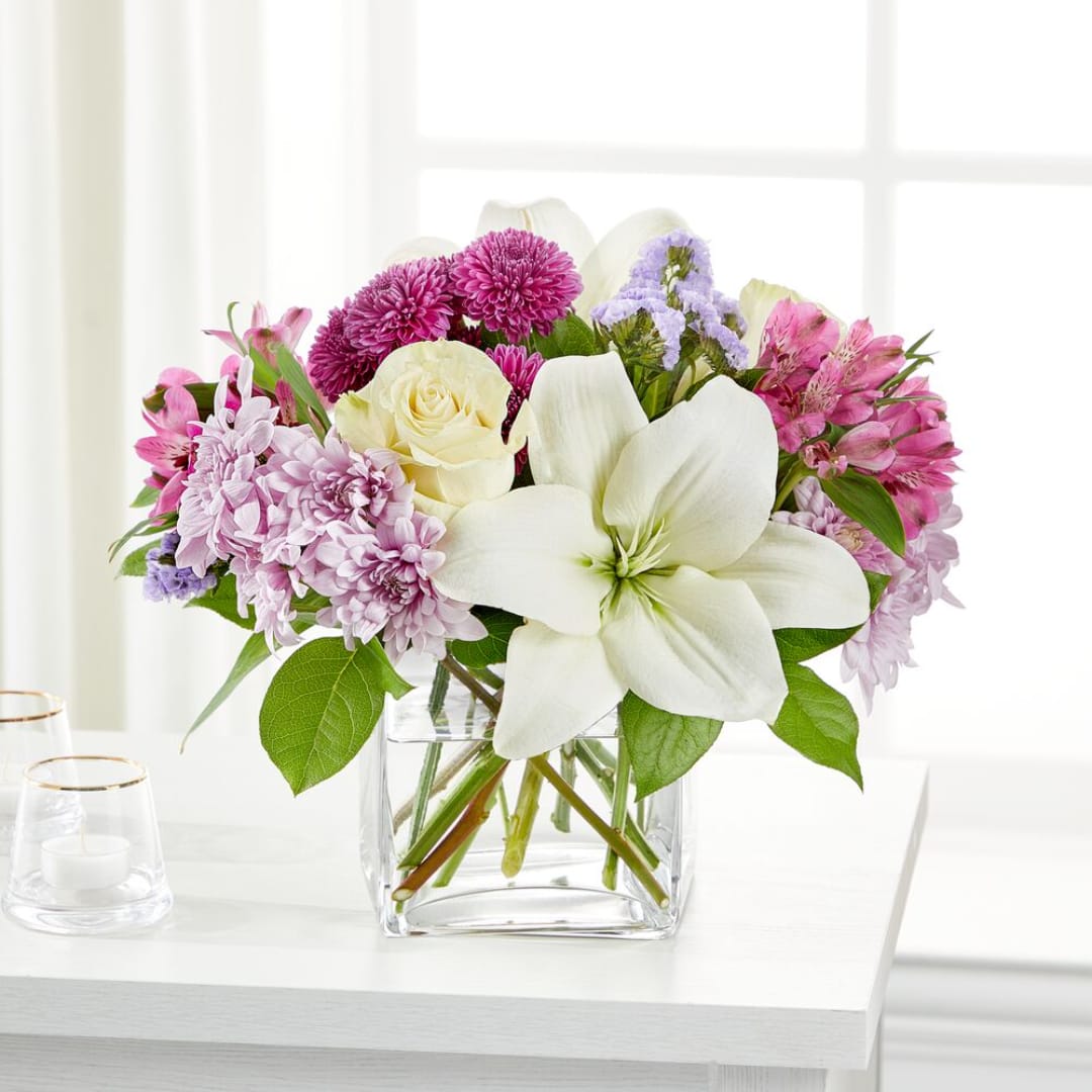 Mixed pink and white flowers arranged in a clear glass vase