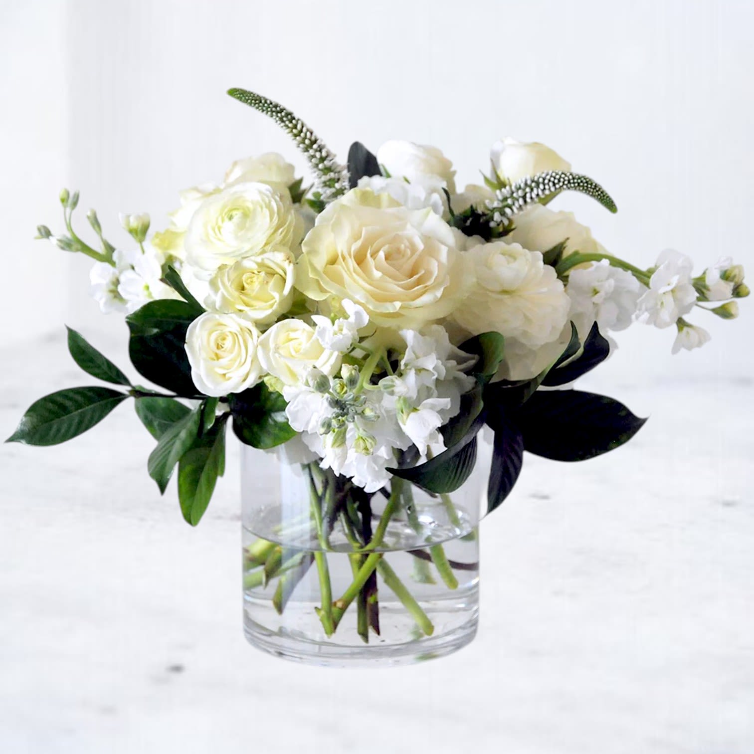 The Edit - The Edit is a refined all-white flower arrangement that celebrates timeless elegance through premium blooms and thoughtful design. Featuring lush white roses, delicate ranunculus, fragrant stock, seasonal flowers, and rich greenery, this arrangement creates a clean, sophisticated look that complements any home, office, or celebration.  Handcrafted in a modern clear glass vase, The Edit is designed with balance, texture, and natural movement, making it equally suited for birthdays, anniversaries, sympathy, housewarmings, thank you gifts, weddings, or everyday moments that deserve something beautiful. Its versatile all-white palette blends effortlessly with any décor while delivering a luxurious, designer-quality presentation.  Every arrangement is handcrafted by the designers at Whiskey Wallflower using the freshest premium flowers available. Seasonal substitutions may occur while preserving the arrangement's signature monochromatic palette, elegant style, and exceptional value.  Hand-delivered throughout Houston, Magnolia, Montgomery, The Woodlands, Conroe, Spring, Tomball, and surrounding communities, The Edit offers understated beauty that never goes unnoticed.