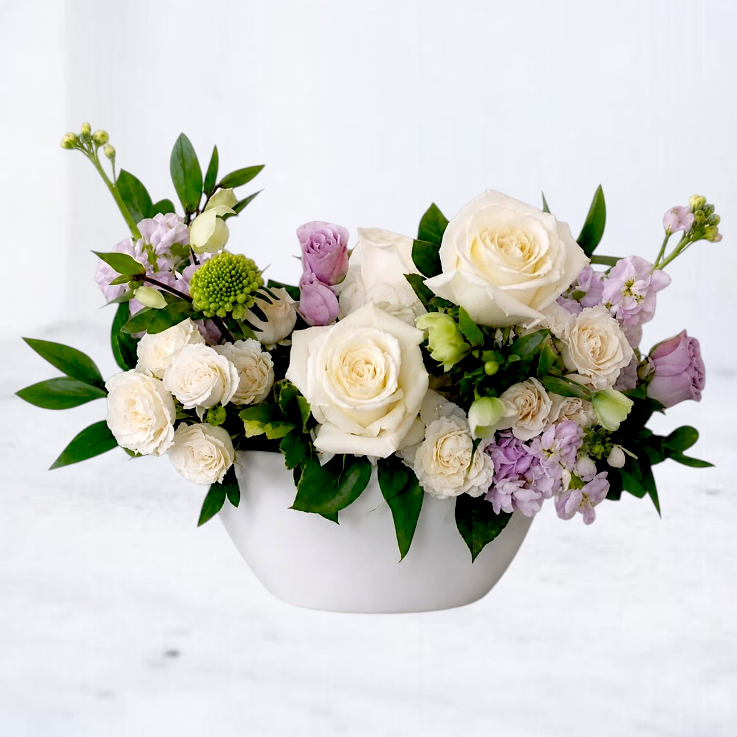 White and lavender roses arranged in a white bowl vase