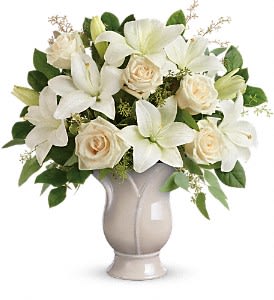 Arrangement of white lilies and cream roses in an ivory ceramic urn vase