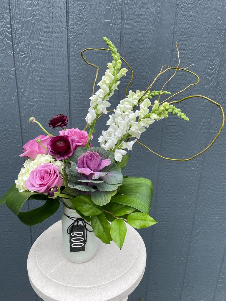 Pink and white floral arrangement in a white vase with looping branches