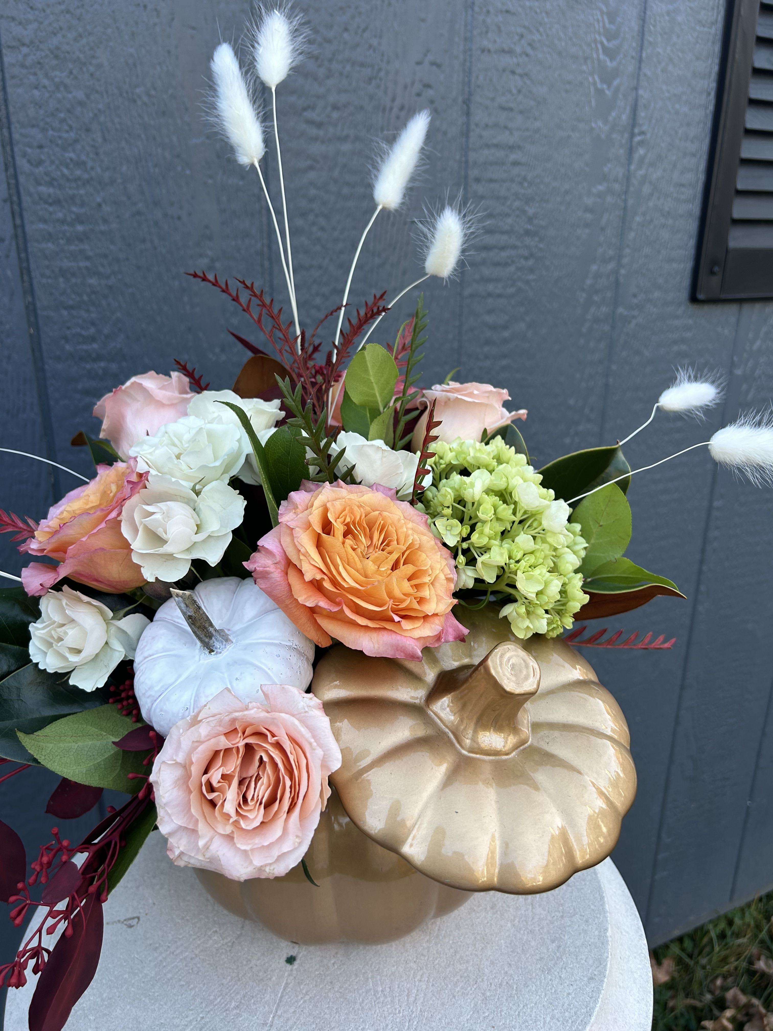 Pumpkin-shaped arrangement with roses, hydrangea, and white bunny tails