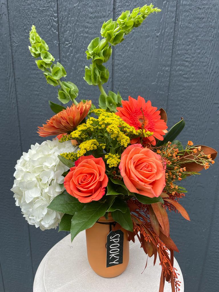 Orange and white floral arrangement in a vase with tall green spikes