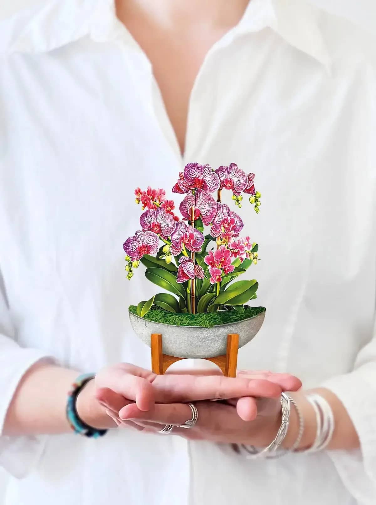 Mini Orchid Oasis Pop-Up Card - Inspired by a tropical getaway, these luxurious and striking orchid blooms embody the lush landscapes of the rainforest. Complete with a mahogany "wood" stand and modern stone planter, this house plant makes the perfect gift and chic home decor.   Measures approx 5.5” high by 5" across
