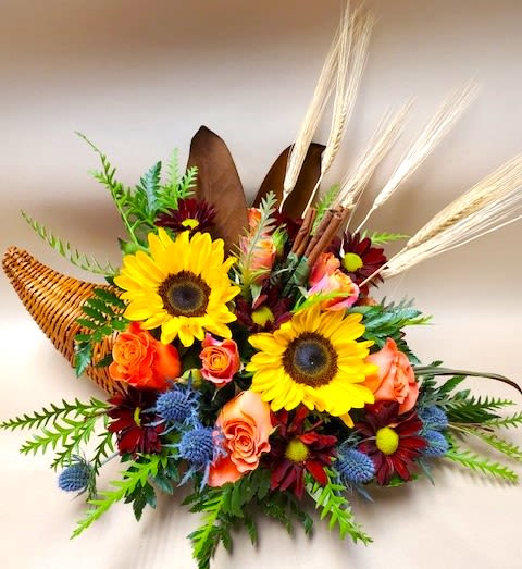 Cornucopia of Flowers - This design is perfect for your Harvest themed party, or just for your table top.  This beautiful design is arranged with Yellow Sunflowers, Orange Roses, Fall Daisies, Orange Spray Roses, Thistle, and an Autumnal array of filler