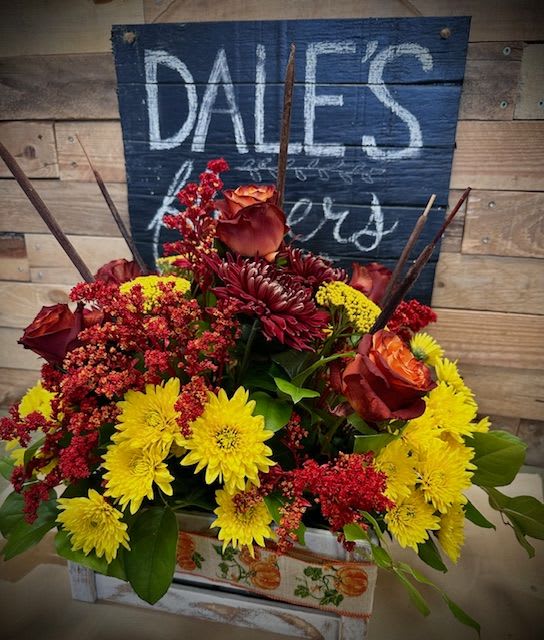 A Country Thanksgiving - Flowers included in design: Orange/Brown Roses, Fall colored poms, Yellow Cremon, Rustic themed filler, assorted greenery.  Arrangement will be designed and displayed in a wooden box wrapped with a Thanksgiving themed ribbon.