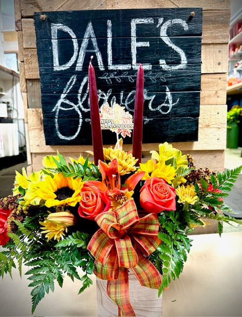 Autumn floral arrangement with sunflowers, roses, and candles in a white container