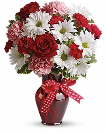 Red and white bouquet in a red vase with a polka-dot ribbon