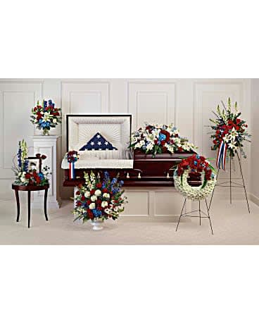 Sympathy floral set with red, white, and blue arrangements around a casket
