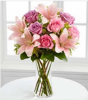 The FTD® Farewell Too Soon™ Bouquet - The FTD® Farewell Too Soon™ Bouquet is a blushingly beautiful way to convey your deepest sympathies for their loss. Pink and lavender roses are offset by pink Asiatic lilies, solidago and lush greens, perfectly arranged in a clear glass vase, to offer warmth and comfort to those facing the loss of their loved one. GOOD bouquet includes 8 stems. Approximately 18"H x 13"W. BETTER bouquet includes 11 stems. Approximately 19"H x 14"W, BEST bouquet includes 16 stems. Approximately 21"H x 17"W. Your purchase includes a complimentary personalized gift message.