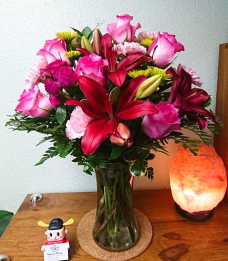 Dressed To Impress Bouquet - Gorgeously girly! Like sending a party in a vase, this breathtaking bouquet of pink roses and lilies is a positively pink-tastic way to celebrate someone special. This fabulously feminine bouquet features hot pink roses, hot pink spray roses, dark pink asiatic lilies, pink carnations, and green button spray chrysanthemums.  Approximately 17 1/2" W x 20" H.