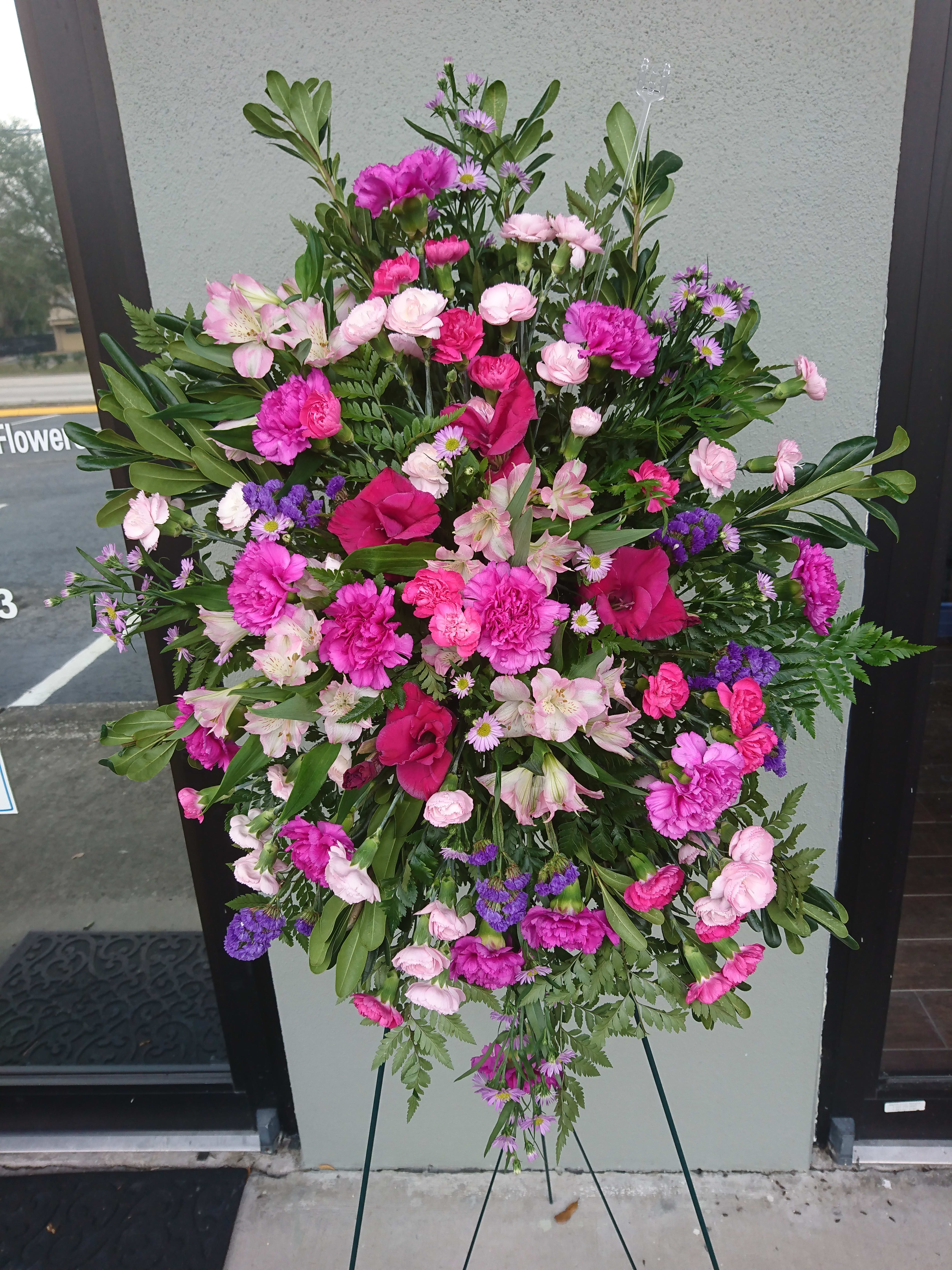Large pink and purple funeral spray on a stand