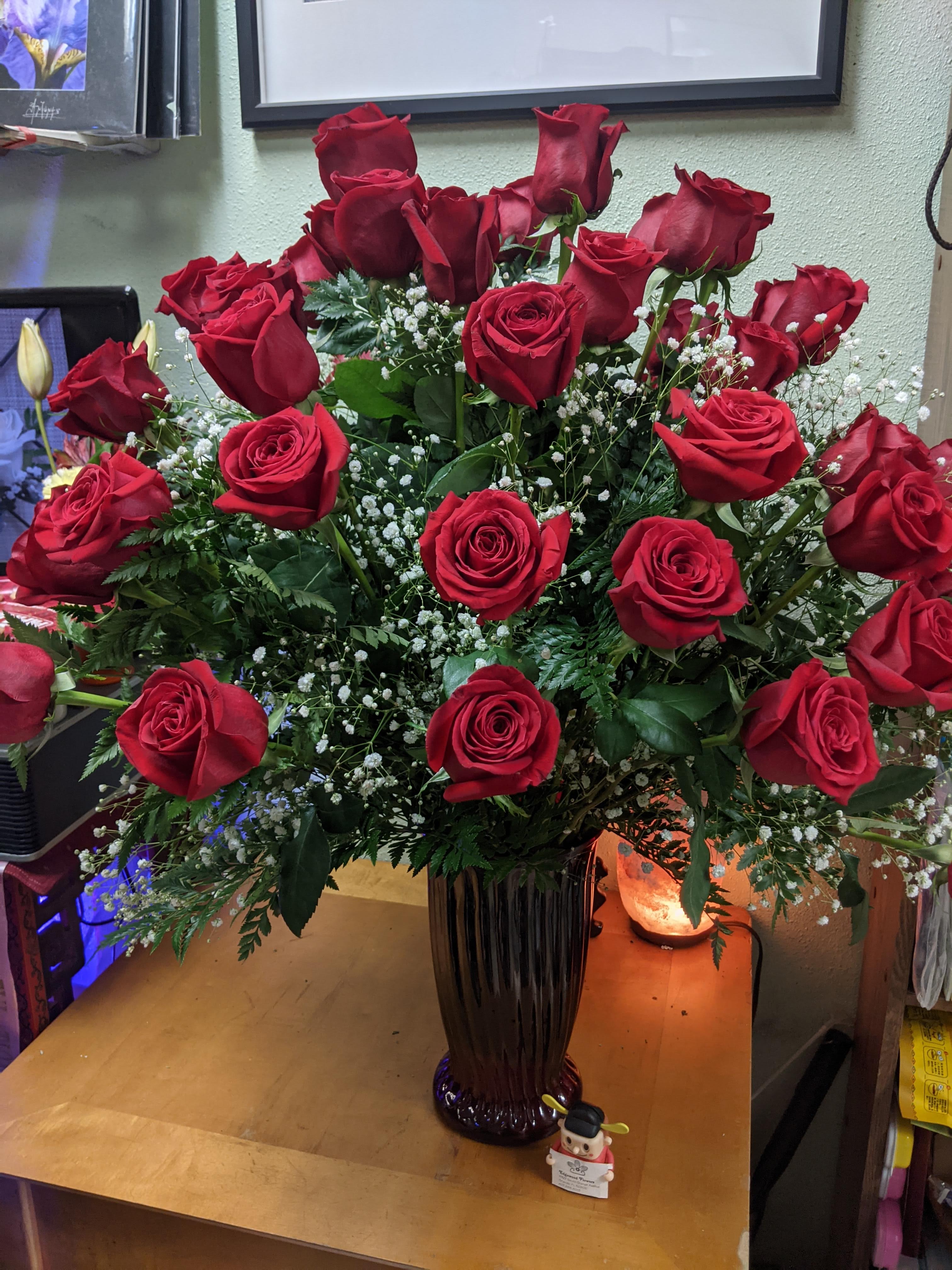 Tall vase arrangement of red roses with baby's breath