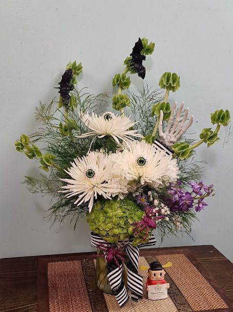 Bouquet of the Recently Deceased - Step into the whimsical world of the afterlife with the Bouquet of the Recently Deceased, inspired by the iconic Beetlejuice movie. This eerie yet elegant arrangement features ghostly white chrysanthemums, vibrant green hydrangeas, rich purple stocks, and purple asters, perfectly complemented by the hauntingly beautiful Bells of Ireland. Beetlejuice-themed accessories, like black and white striped accents and quirky embellishments, add a playful, gothic charm. Perfect for Halloween or any fan of the film, this bouquet brings a touch of the supernatural to life!