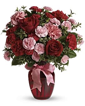 Red roses and pink carnations in a vase with a pink ribbon