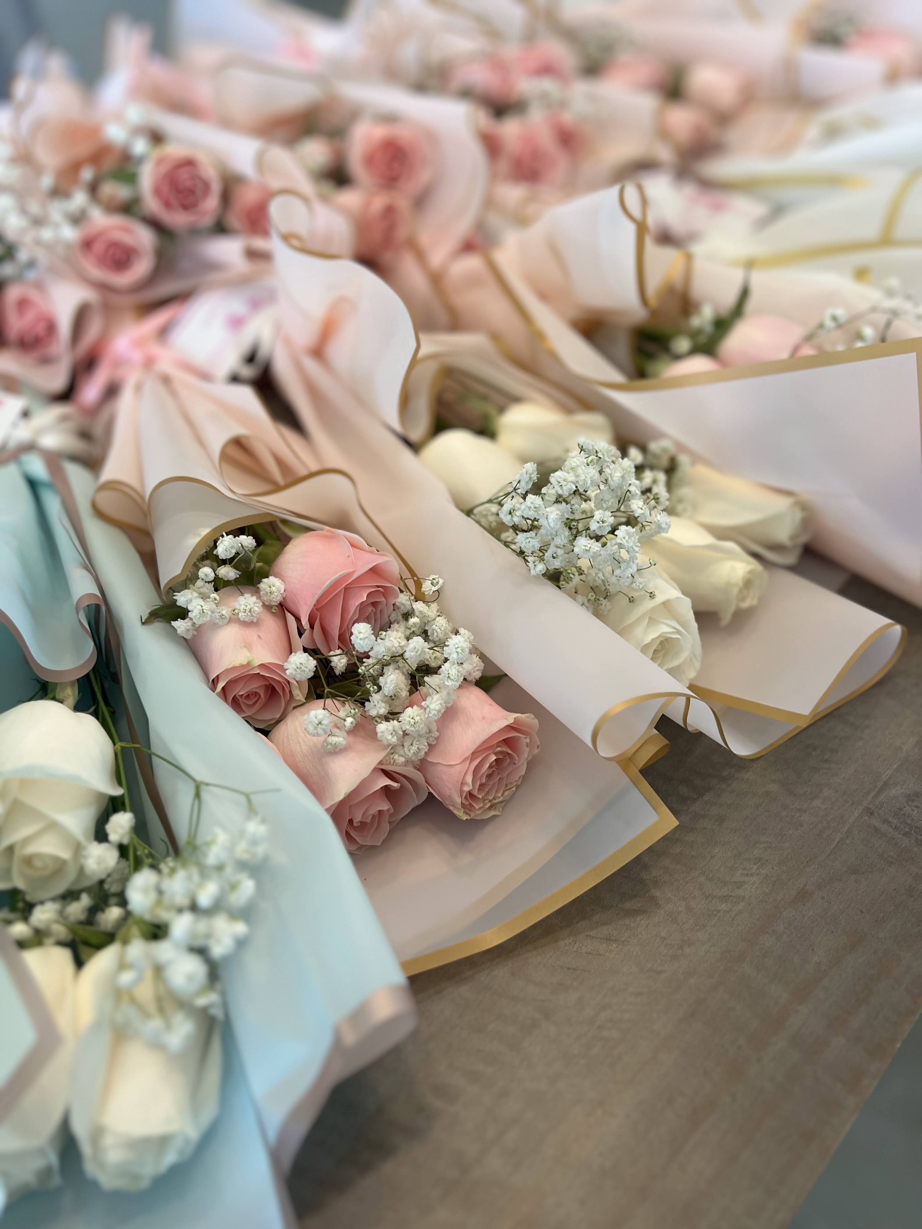 Several pastel rose bouquets wrapped in paper with baby's breath
