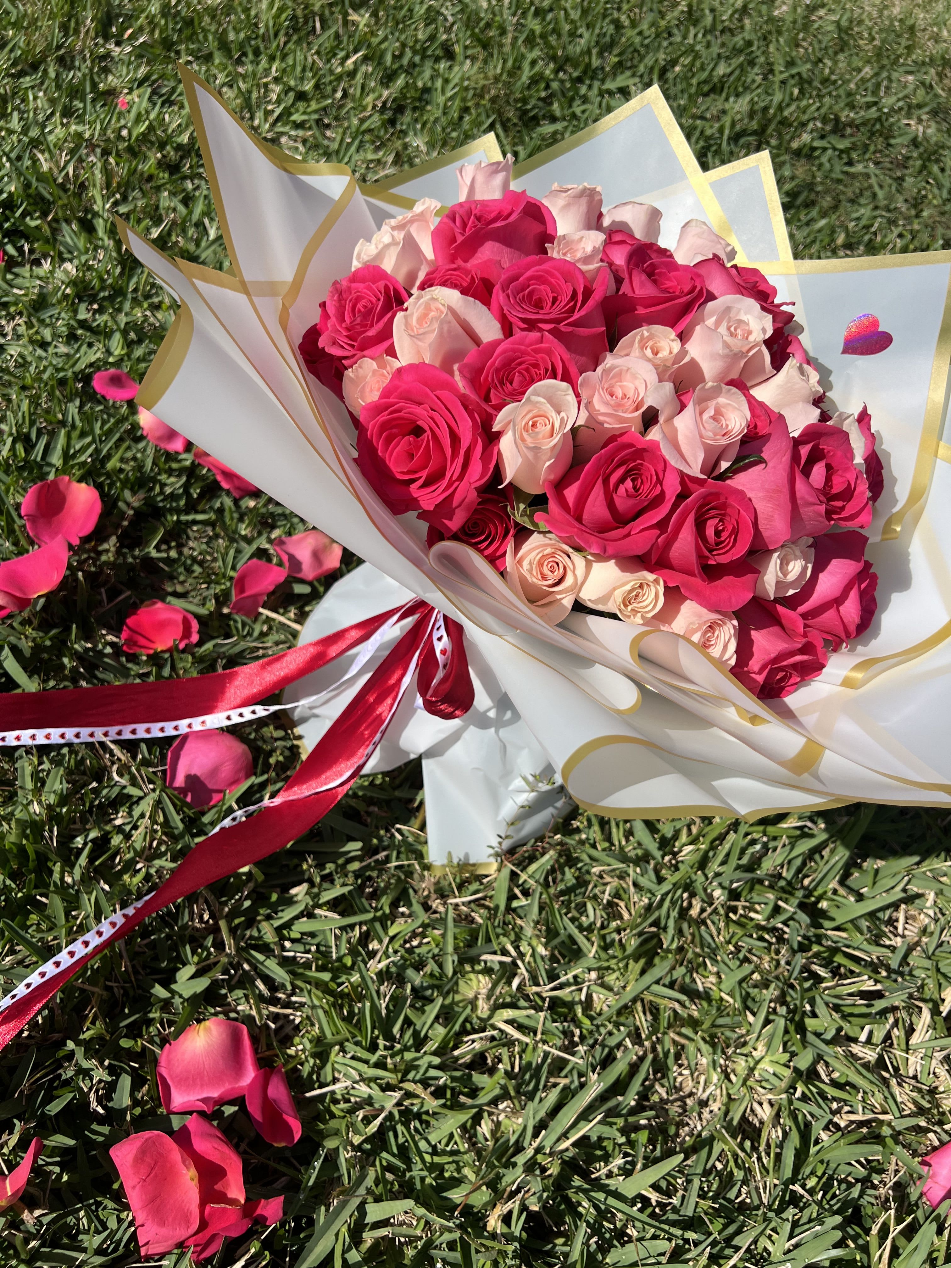 Bouquet of pink and blush roses wrapped in white paper with gold trim