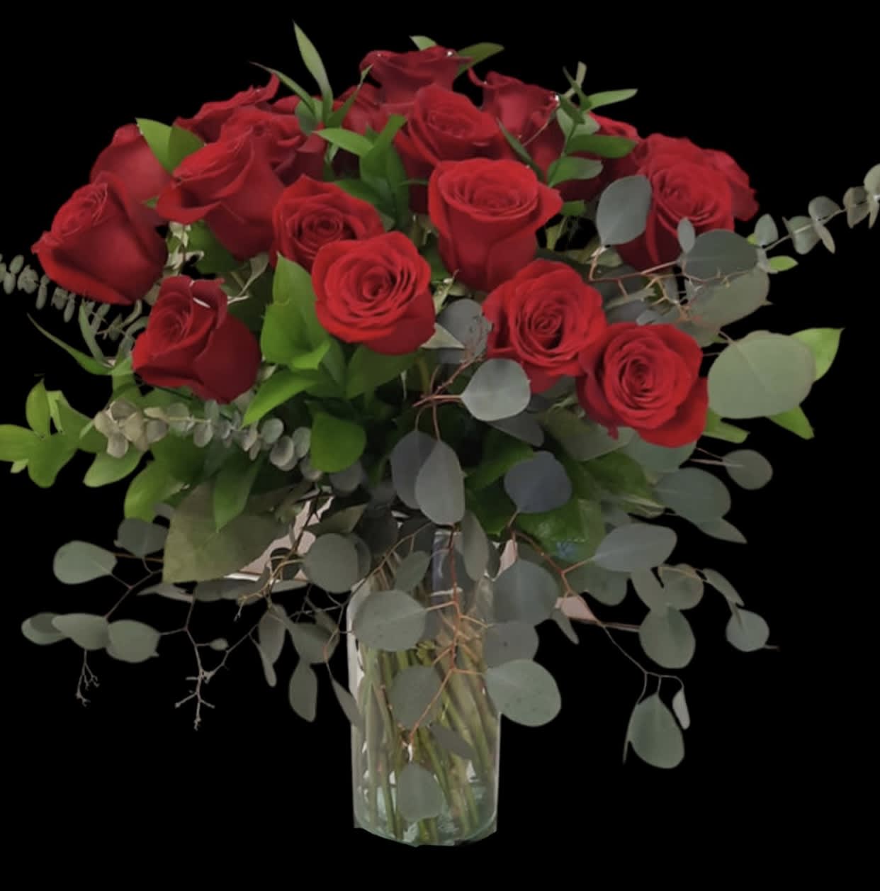 Bouquet of red roses in a clear glass vase with eucalyptus