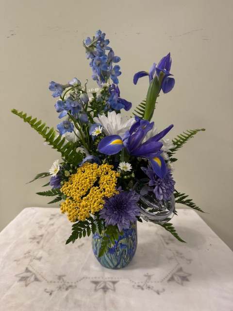 Blue and yellow mixed flower arrangement in a glass vase