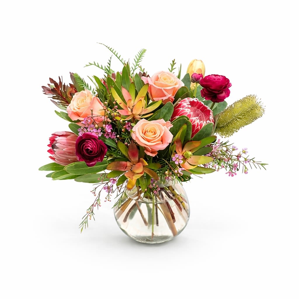 Mixed bouquet of pink and peach flowers in a clear glass vase