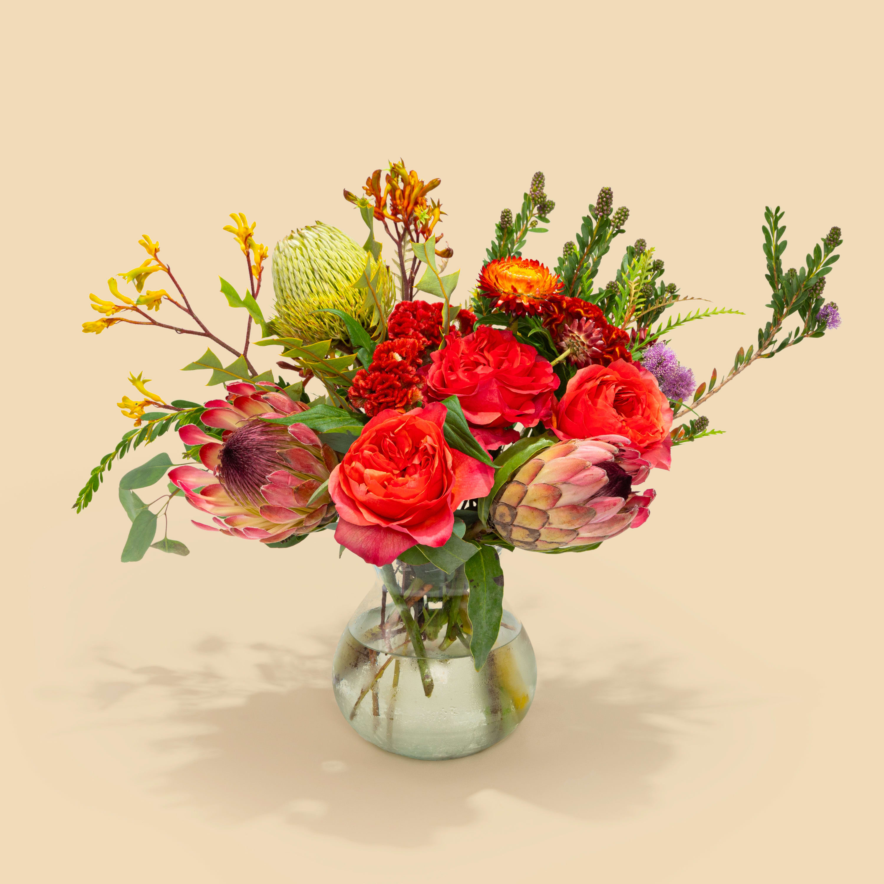 Mixed bouquet of red and orange flowers in a glass vase