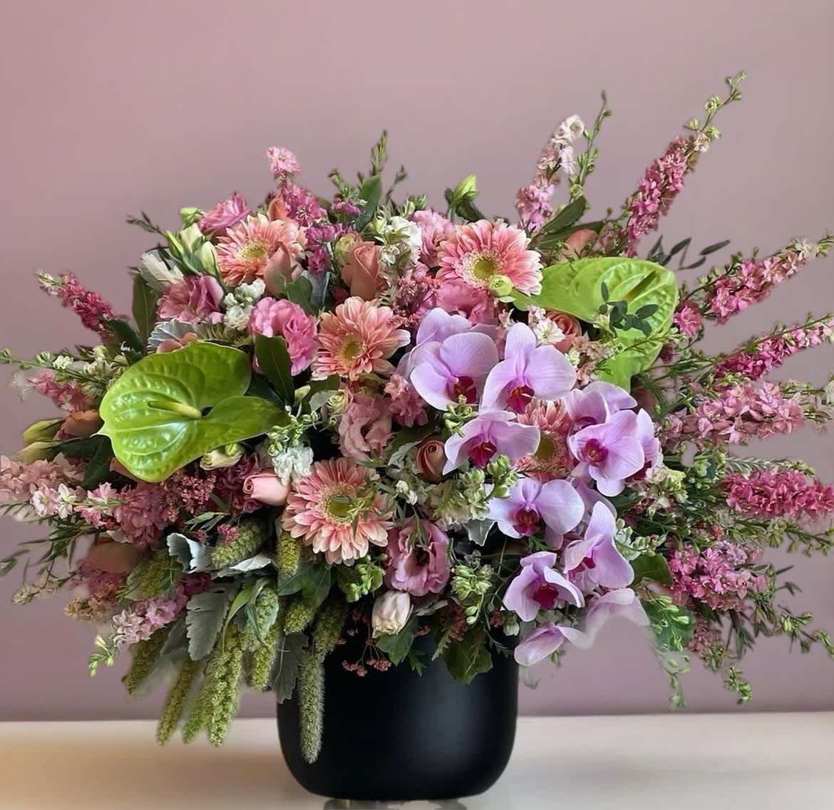 Pink mixed bouquet with orchids and gerbera daisies in a black vase