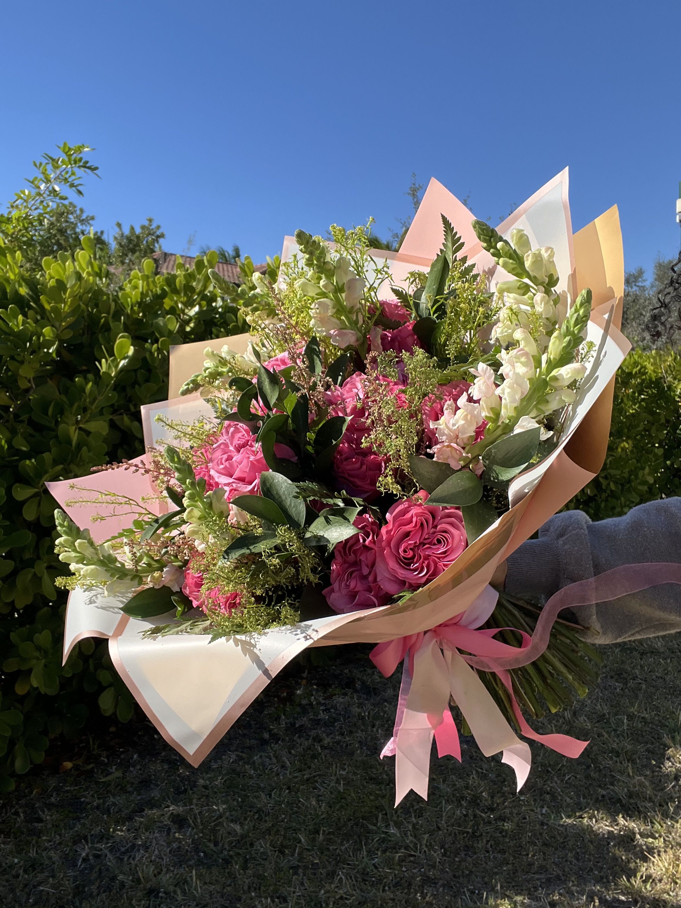 Bouquet of pink roses and white snapdragons wrapped in pastel paper