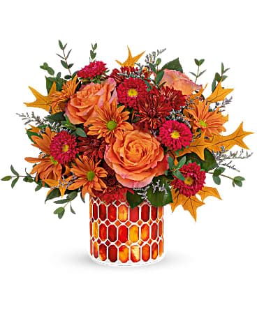 Teleflora's Autumn Aglow Bouquet - As magical as the first falling leaf, this majestic rose bouquet is presented to perfection in a magnificent mosaic vase of shimmering stained glass. This beautiful bouquet includes orange roses, red matsumoto asters, bronze cushion spray chrysanthemums, bronze daisy spray chrysanthemums, purple limonium and parvifolia eucalyptus, accented with preserved oak leaves. Delivered in an Autumn Radiance Mosaic vase.