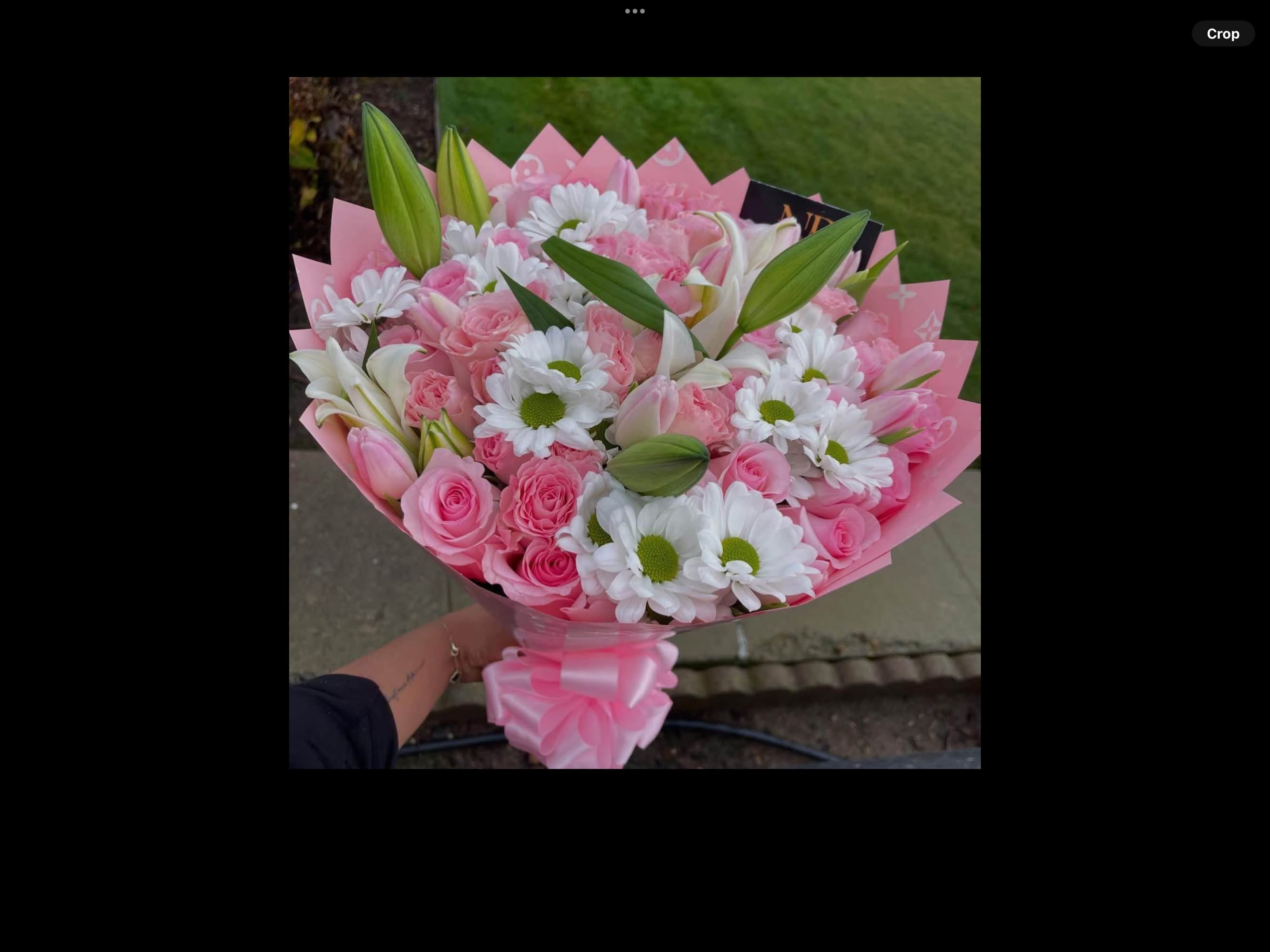 Pink bouquet of roses, daisies, and lilies wrapped in pink paper
