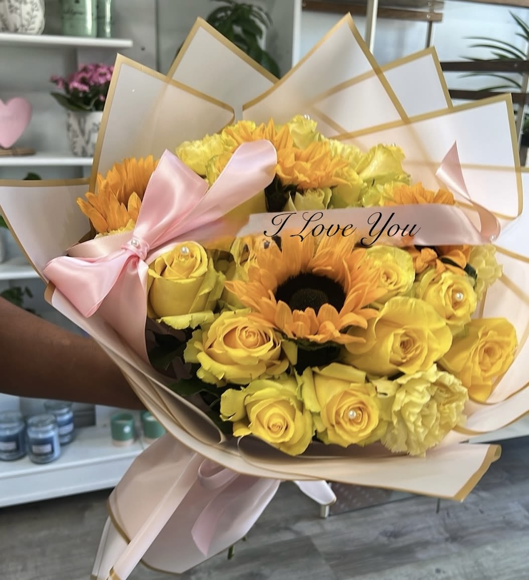 Yellow roses and orange sunflowers in pink wrapping with a ribbon