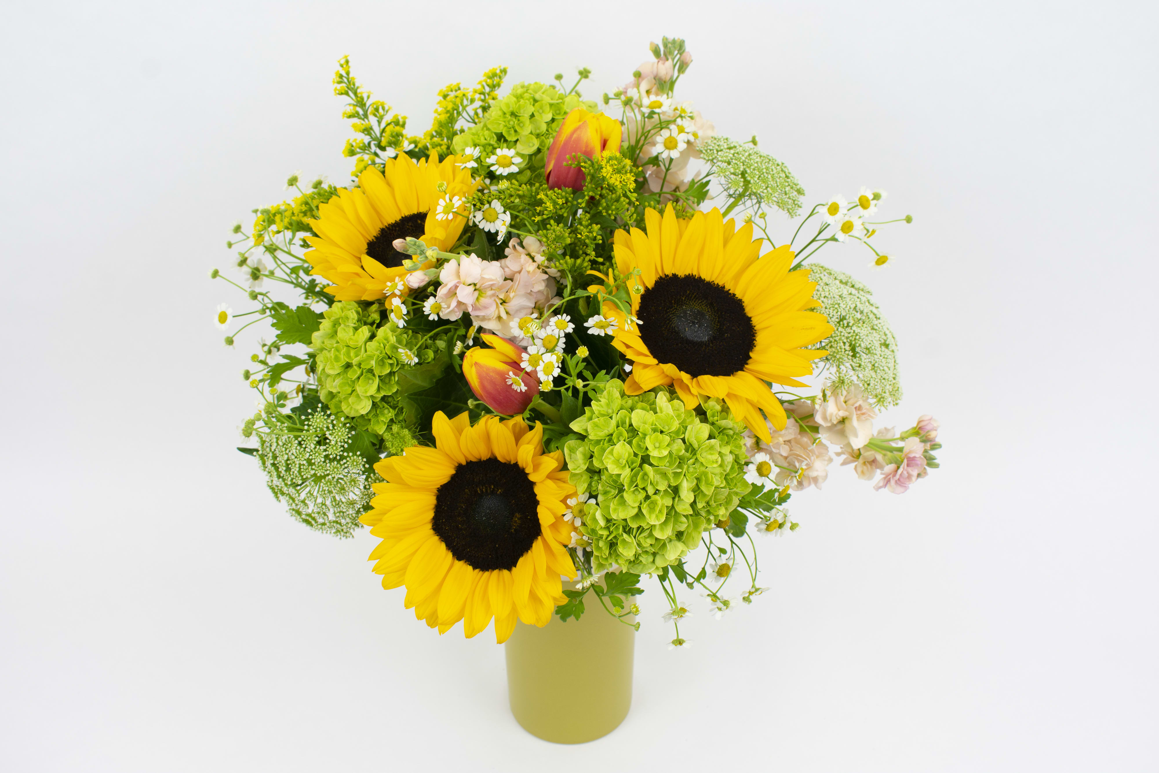 Sunflower bouquet with green hydrangeas and small white flowers in a vase