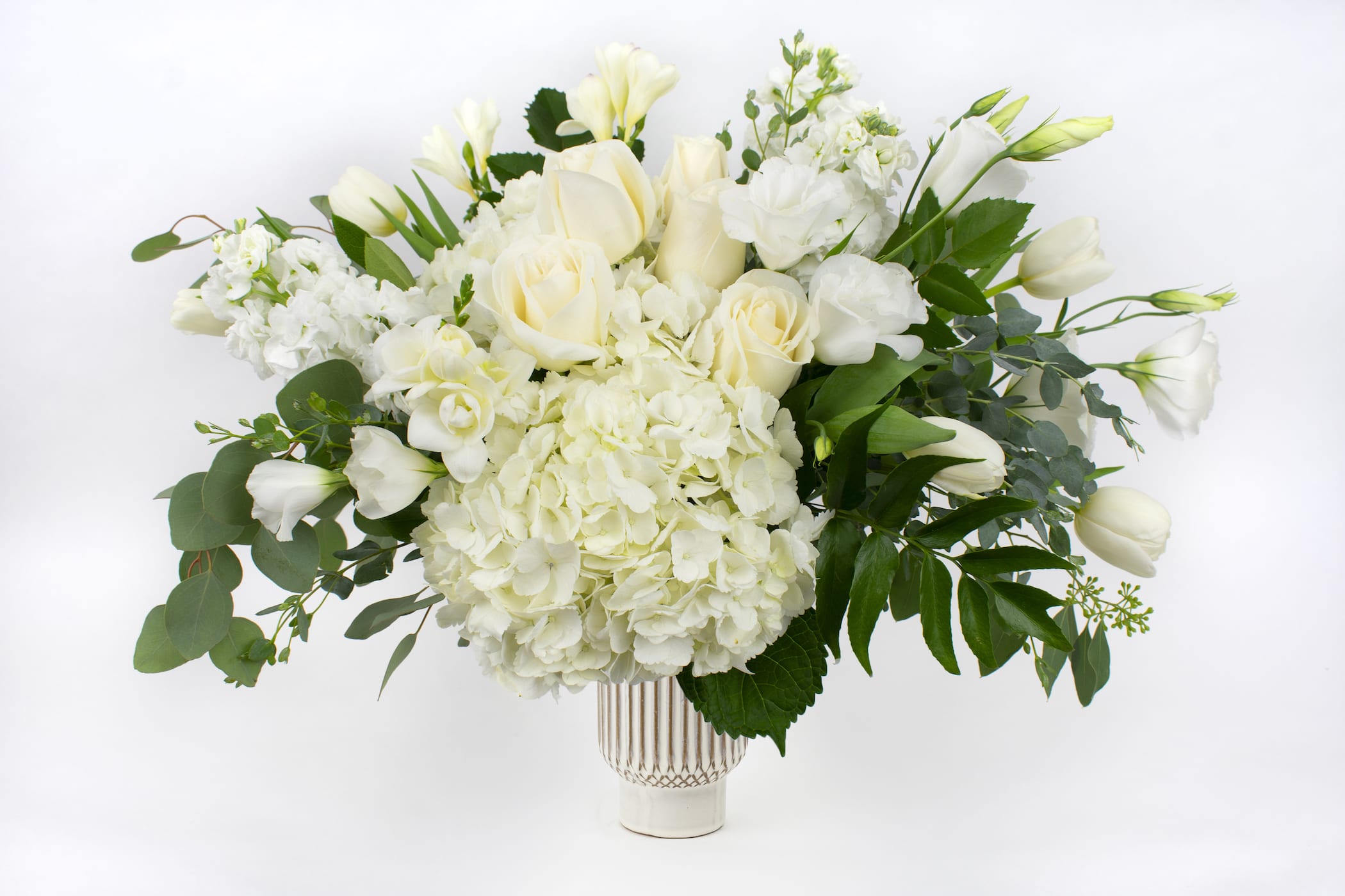 White roses and hydrangeas arranged in a clear vase