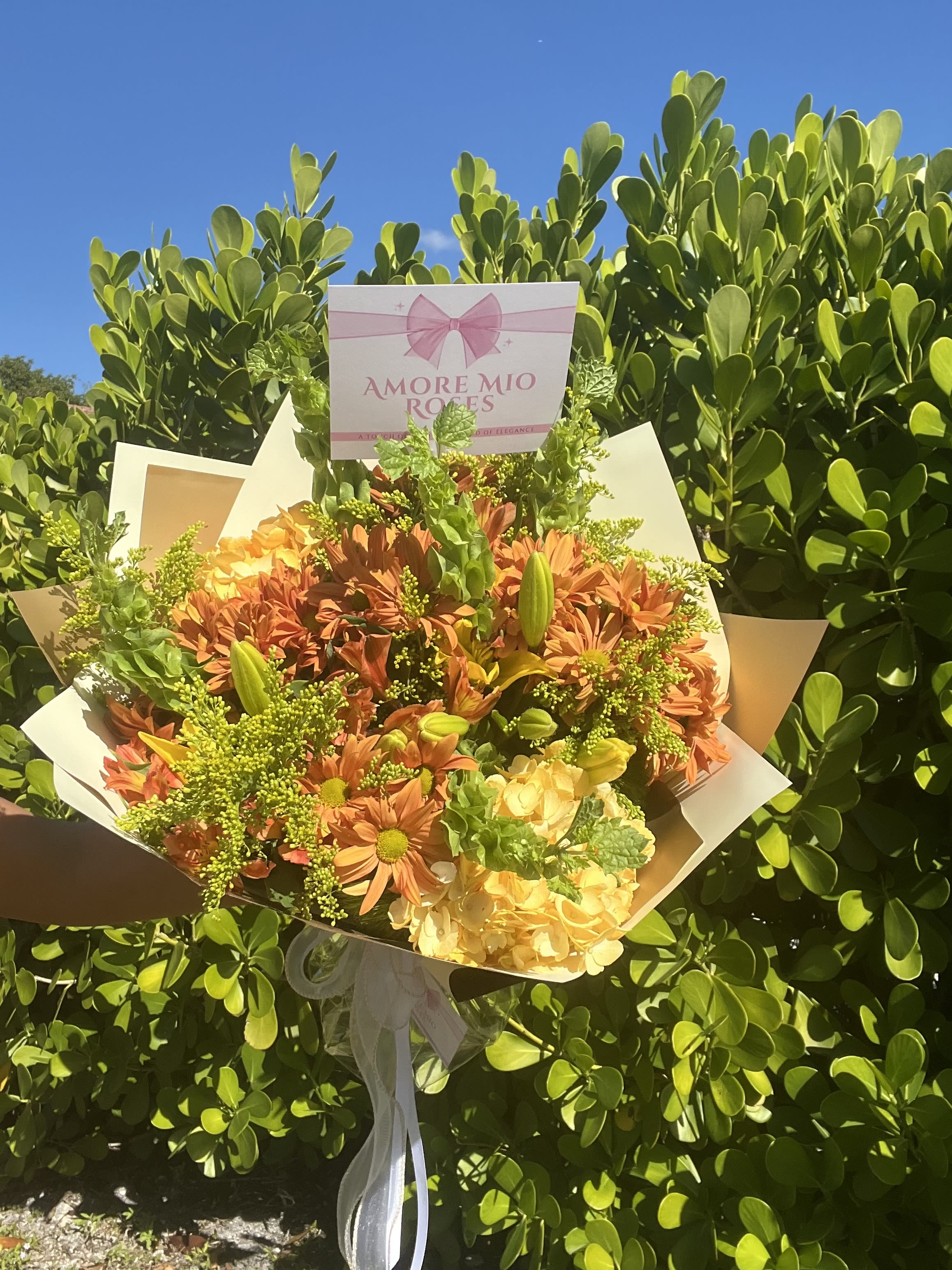 Bouquet of orange and yellow flowers with a pink sign