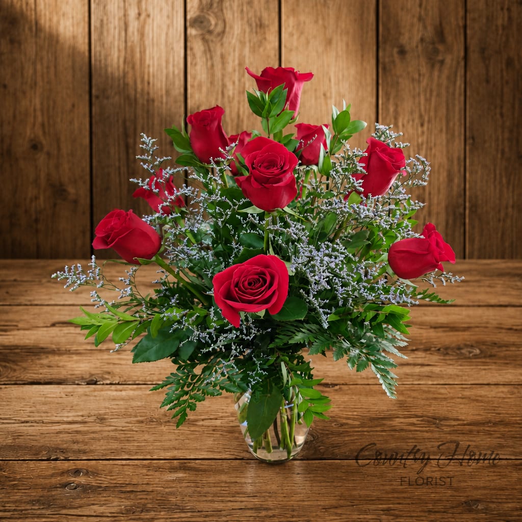 Red roses arranged in a clear glass vase with airy filler