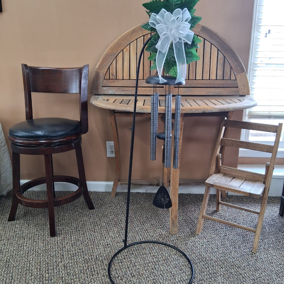 Wind chime with a white bow hanging on a black stand
