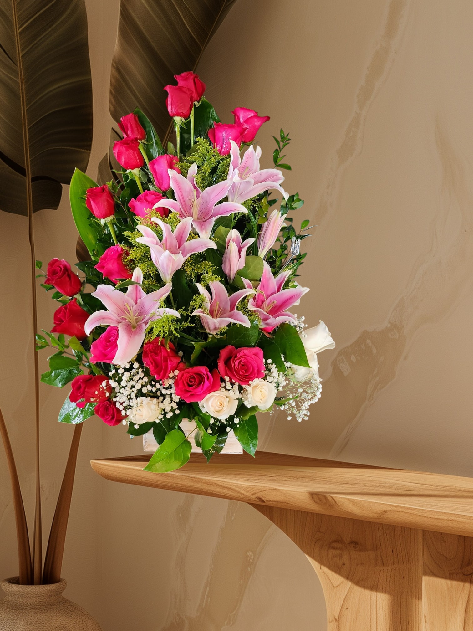 Pink lilies and roses arranged in a clear vase