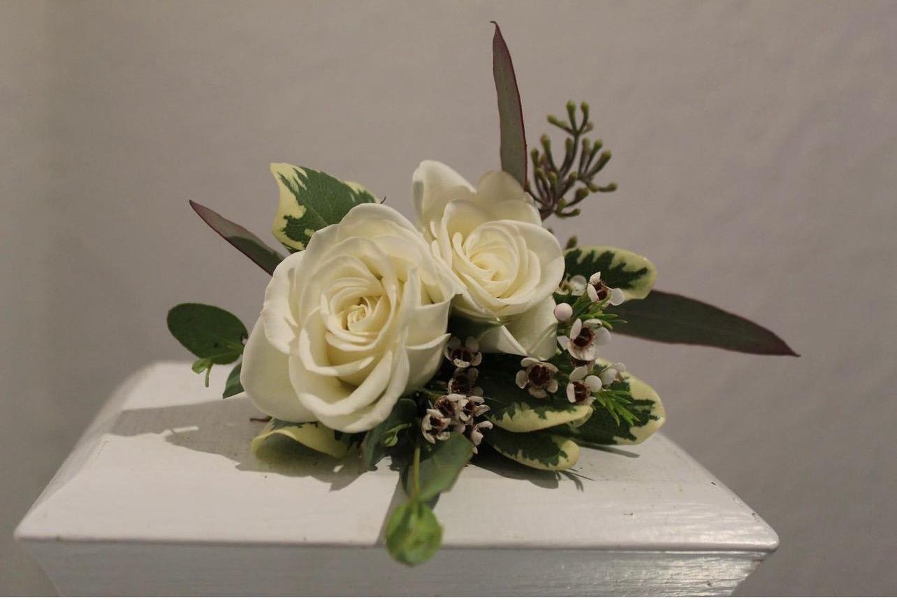 Small arrangement of two ivory roses with accent blooms and foliage