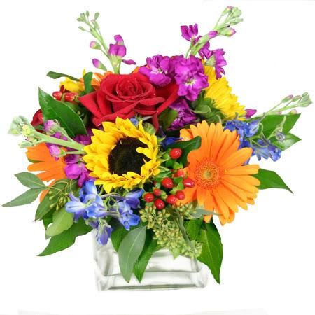 Colorful bouquet in a clear glass vase with roses, gerbera daisies, and sunflowers