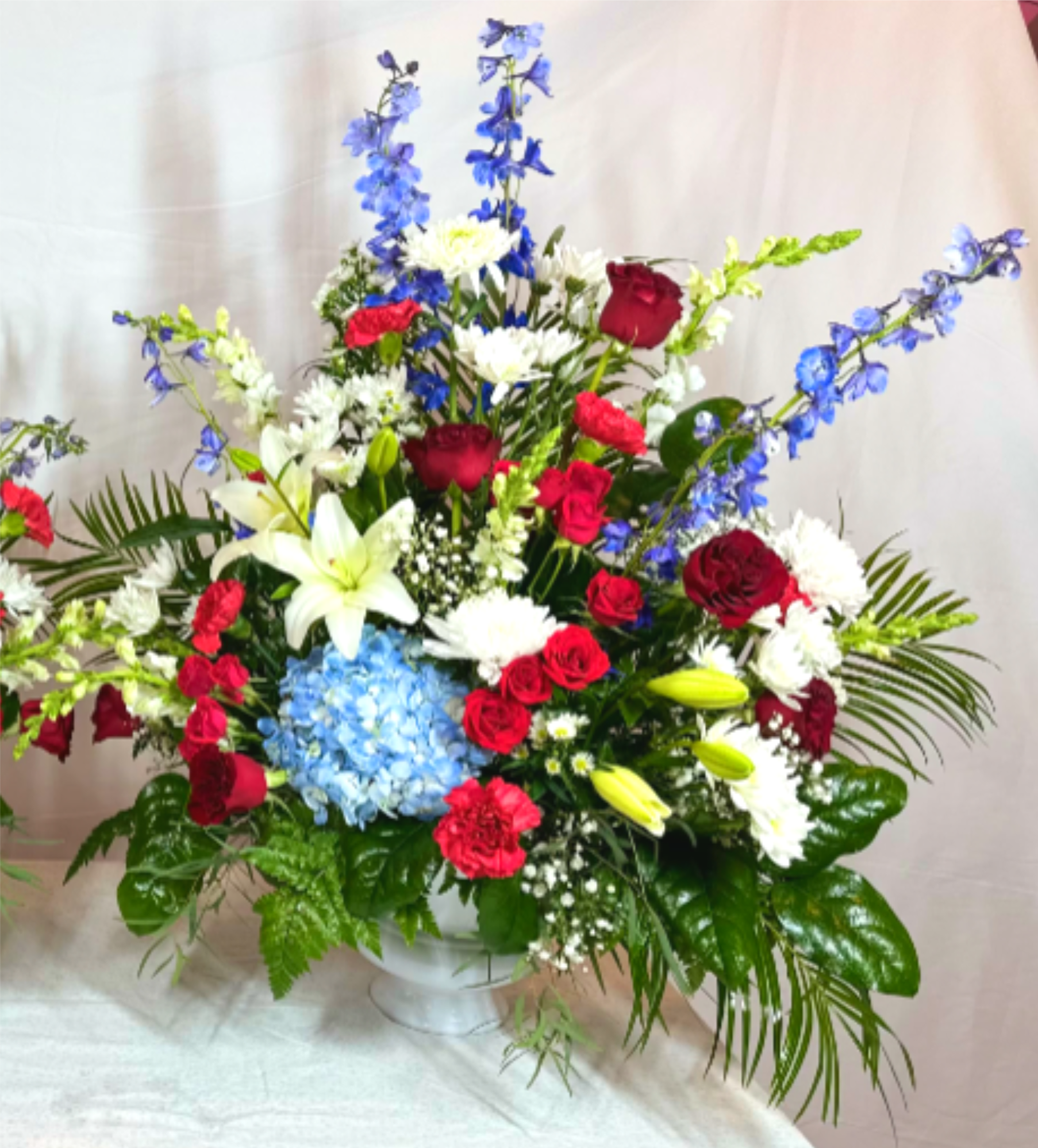 Thank you for your Service Standing Vase - A wonderful way to pay respects to a service member is with this elegant red, white, and blue arrangement. This beautiful design will honor the memory of a friend or loved one who was in the armed forces. This is wonderful as a single arrangement, or, can be ordered  in multiples for use at the head and foot of a casket.