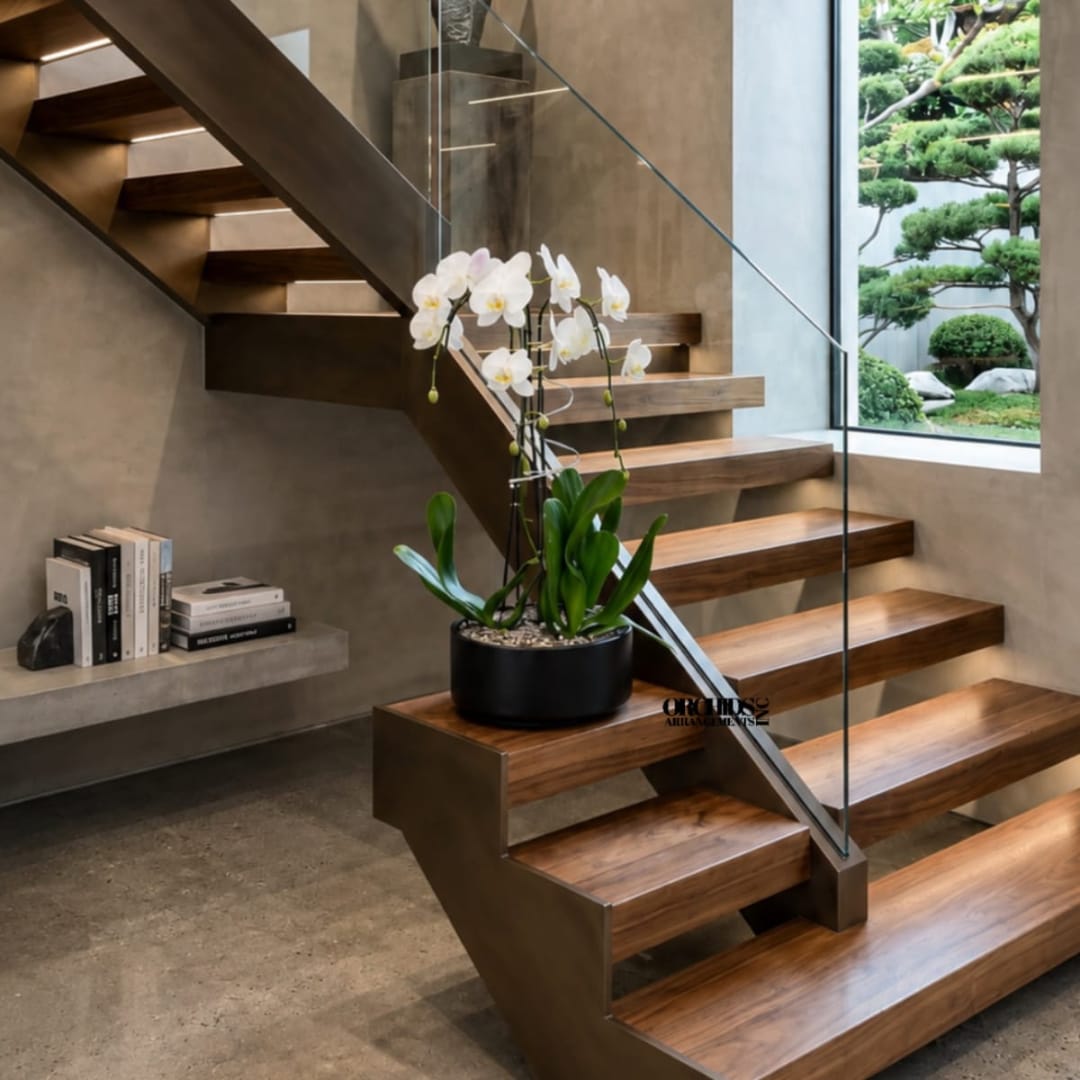White orchid plant in a black pot on a wooden staircase landing