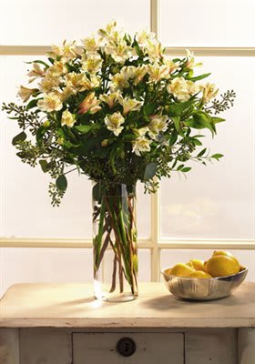 Tall bouquet of pale yellow flowers in a clear glass vase