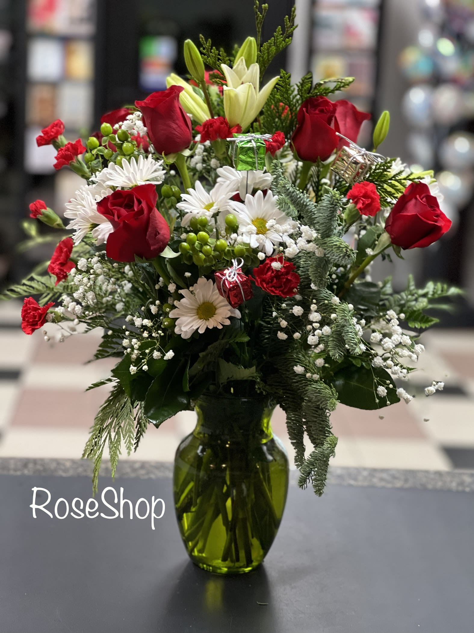 Christmas Joy - This joyful red  and white bouquet is sure to light up their home with holiday delight. Thus fresh bouquet includes Christmas greens, roses, carnarions, daisies and more.  Approx 16”H x 14”W